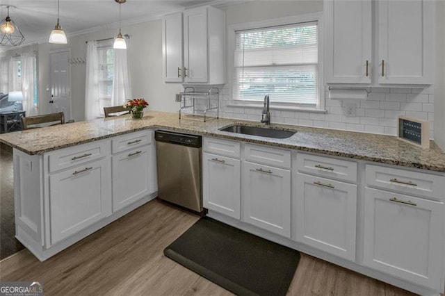 kitchen with pendant lighting, backsplash, sink, stainless steel dishwasher, and white cabinetry