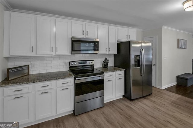 kitchen with decorative backsplash, light wood-type flooring, dark stone counters, stainless steel appliances, and white cabinetry