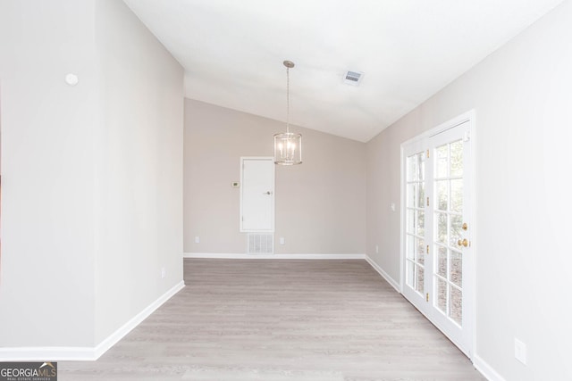 unfurnished room featuring an inviting chandelier, vaulted ceiling, and light wood-type flooring