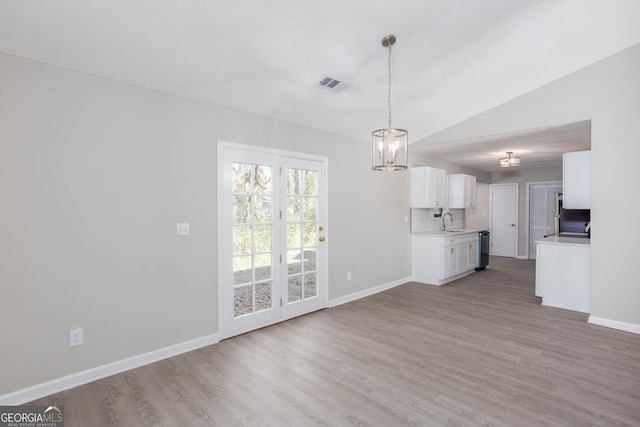 unfurnished living room with lofted ceiling, light wood-type flooring, and sink