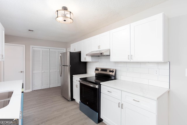 kitchen featuring white cabinetry, stainless steel appliances, a textured ceiling, and light hardwood / wood-style floors