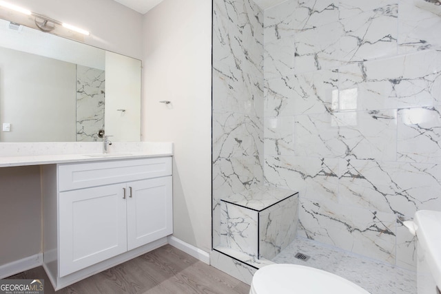 bathroom with tiled shower, vanity, hardwood / wood-style flooring, and toilet