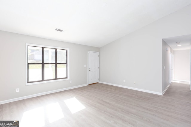 unfurnished room with light wood-type flooring and vaulted ceiling