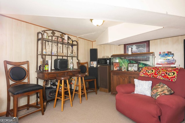 interior space with light carpet, light brown cabinets, lofted ceiling, and wooden walls