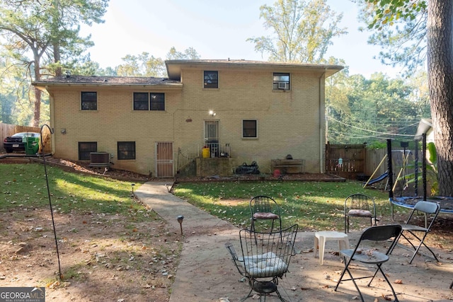 rear view of property with a lawn, central AC, a patio, and a trampoline