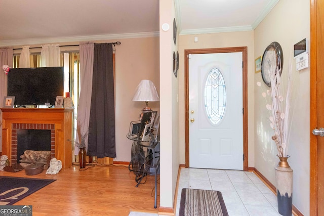 foyer entrance with light hardwood / wood-style flooring, crown molding, and a brick fireplace