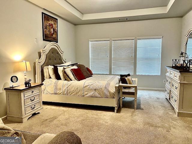 bedroom featuring light colored carpet and a tray ceiling