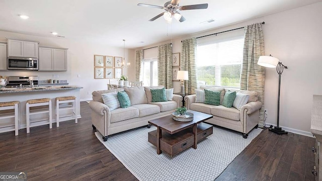 living room featuring ceiling fan with notable chandelier, dark hardwood / wood-style flooring, and sink