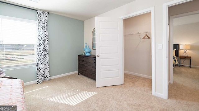 carpeted bedroom featuring a walk in closet and a closet