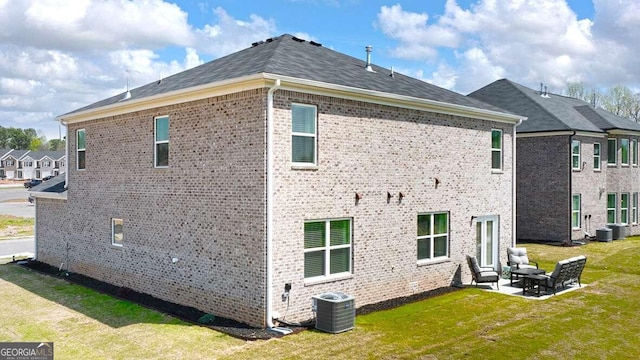 back of house with central AC unit, a patio area, and a lawn