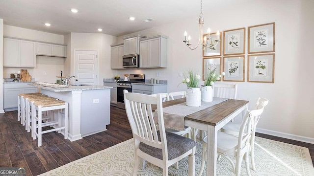 dining area with a chandelier, sink, and dark wood-type flooring