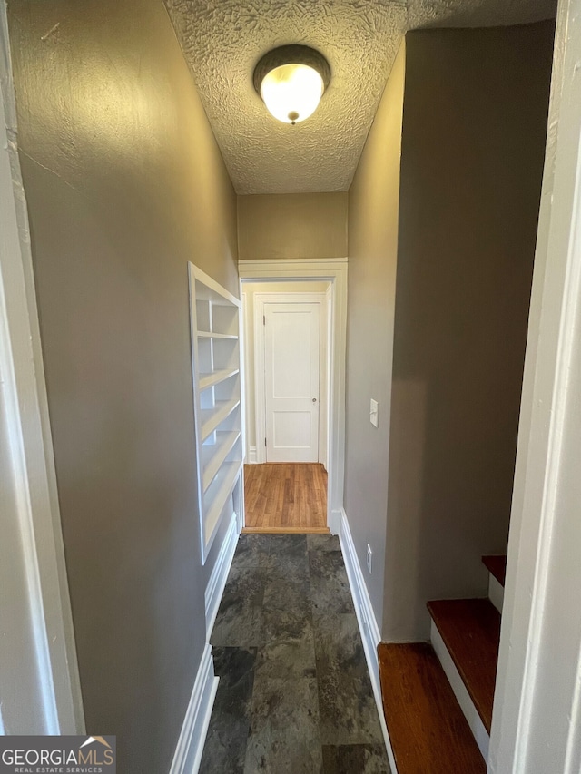 hall with dark wood-type flooring and a textured ceiling