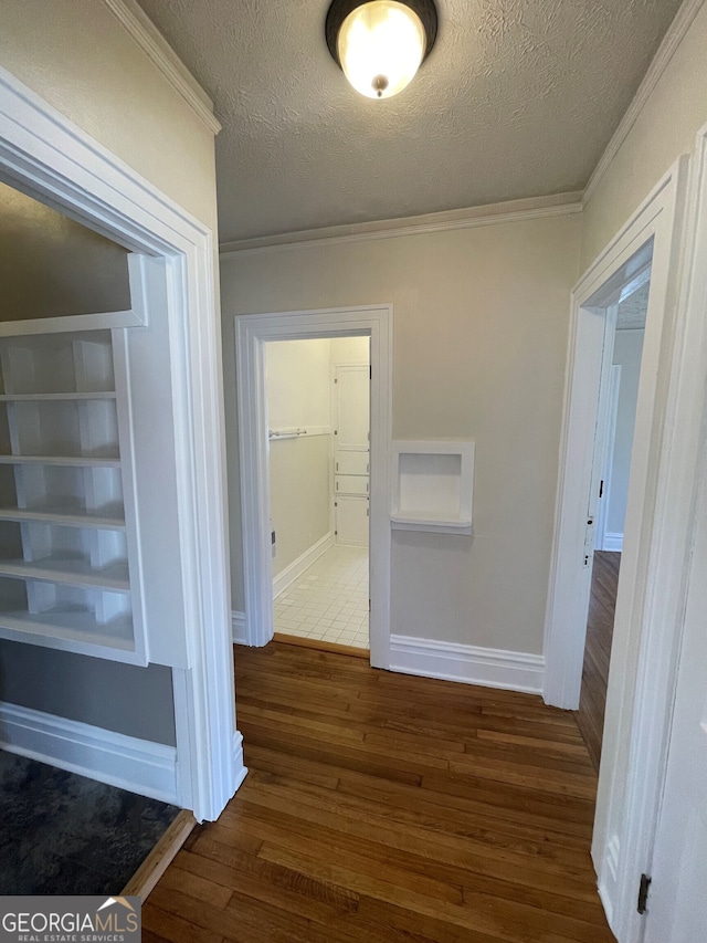 corridor with ornamental molding, a textured ceiling, and dark hardwood / wood-style flooring