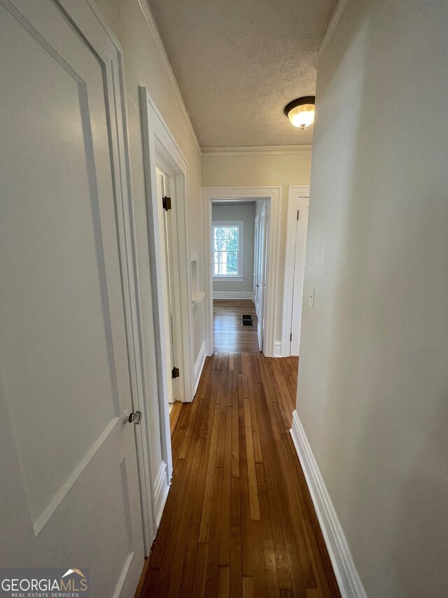 corridor with crown molding, a textured ceiling, and dark hardwood / wood-style flooring