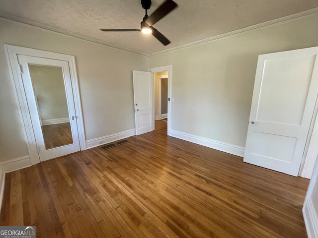unfurnished bedroom featuring ceiling fan, ornamental molding, a textured ceiling, and hardwood / wood-style floors