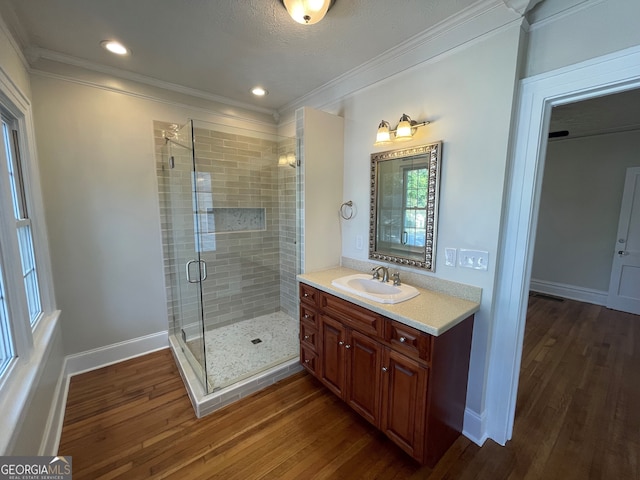 bathroom with a textured ceiling, an enclosed shower, vanity, hardwood / wood-style flooring, and ornamental molding