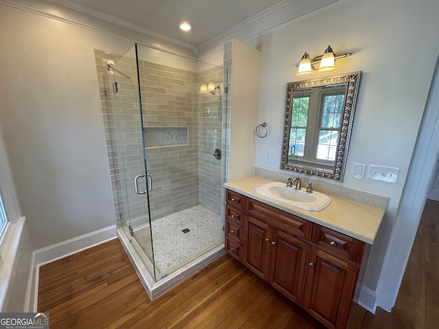 bathroom featuring vanity, crown molding, hardwood / wood-style flooring, and a shower with shower door