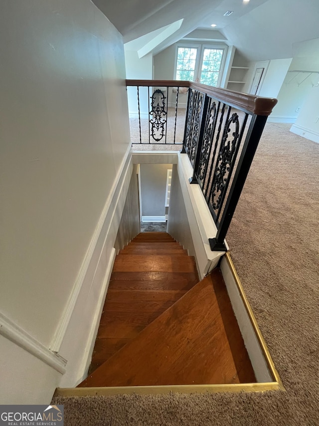 stairway featuring carpet floors and vaulted ceiling