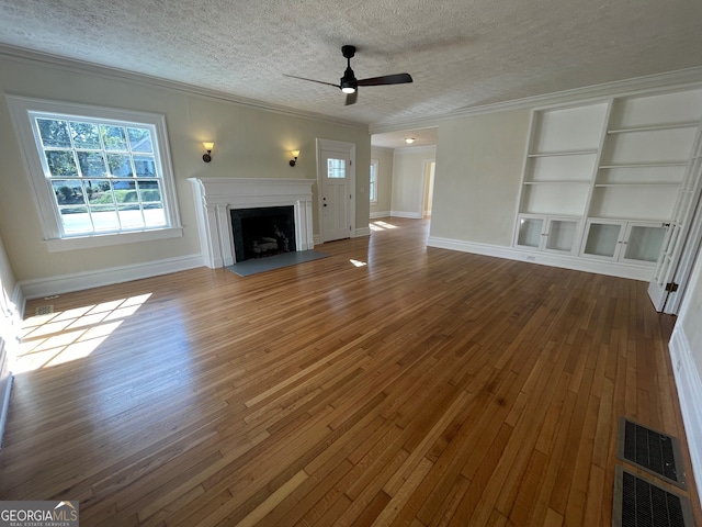 unfurnished living room featuring crown molding, wood-type flooring, and a textured ceiling