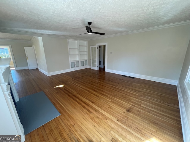 unfurnished living room with ceiling fan, crown molding, wood-type flooring, and built in shelves