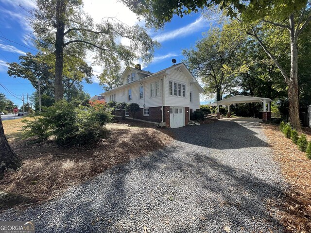 425 E 9th St SE, Rome, GA 30161 - view of side of home with gravel driveway, brick siding, a chimney, and a detached carport