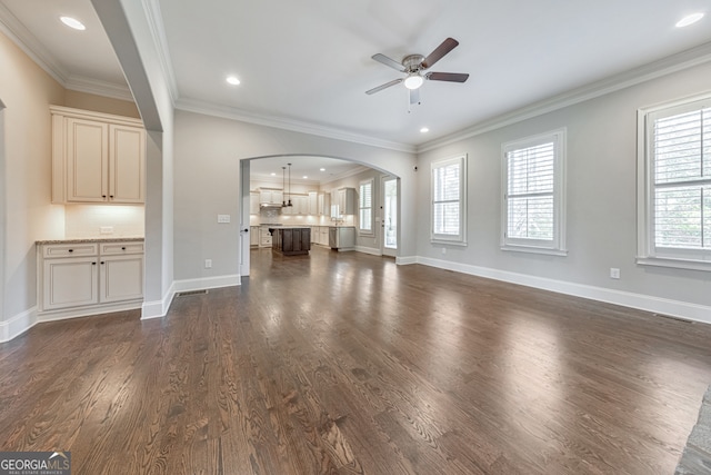 unfurnished living room featuring ceiling fan, ornamental molding, and dark wood-type flooring