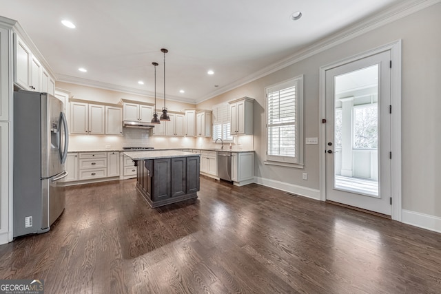 kitchen featuring appliances with stainless steel finishes, a center island, decorative light fixtures, and dark wood-type flooring