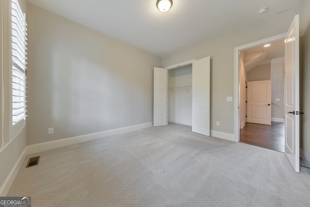 unfurnished bedroom with carpet, vaulted ceiling, and a closet