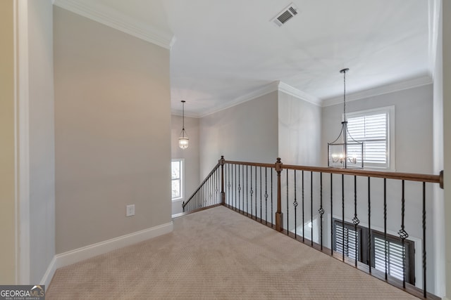 hall with carpet flooring, ornamental molding, a wealth of natural light, and a chandelier