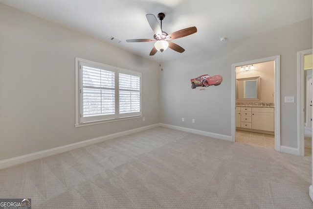 unfurnished bedroom featuring ensuite bath, light carpet, and ceiling fan