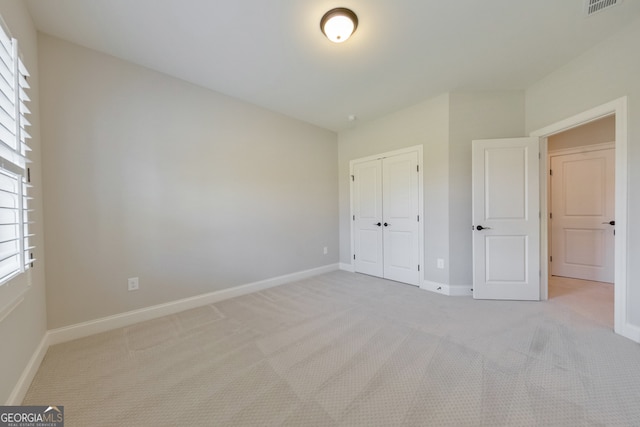 unfurnished bedroom with light colored carpet and a closet