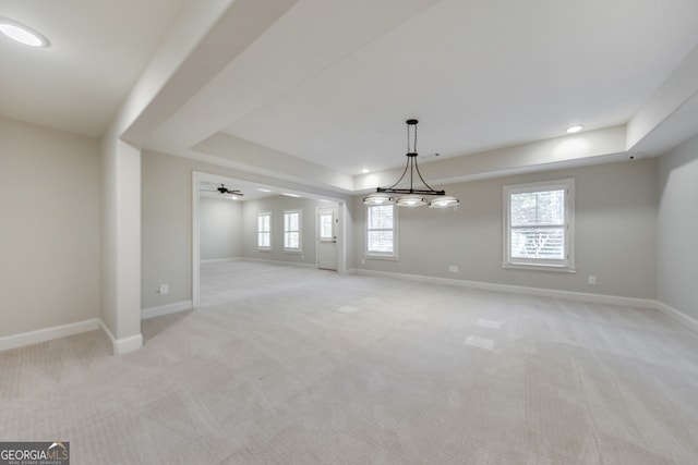 carpeted empty room featuring ceiling fan and a tray ceiling