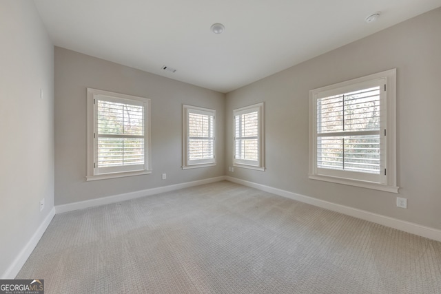 spare room featuring light carpet and a wealth of natural light