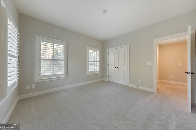 unfurnished bedroom with light colored carpet and a closet