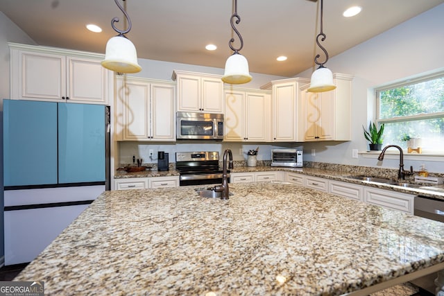 kitchen featuring sink, hanging light fixtures, a center island, light stone counters, and stainless steel appliances