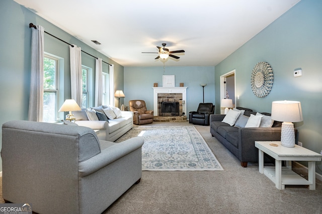 carpeted living room with ceiling fan and a fireplace