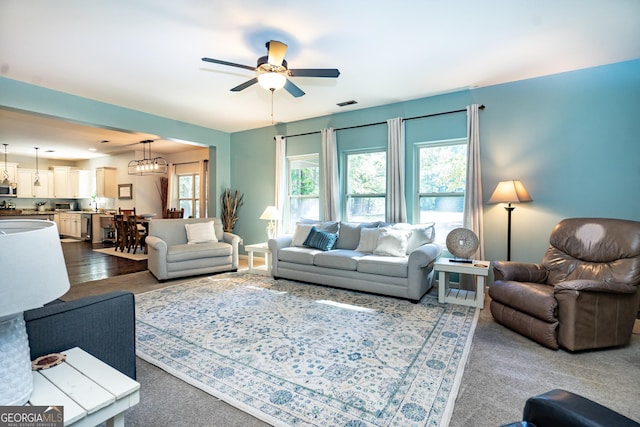 living room featuring carpet and ceiling fan with notable chandelier