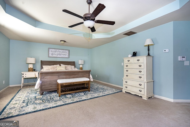 carpeted bedroom with ceiling fan and a tray ceiling