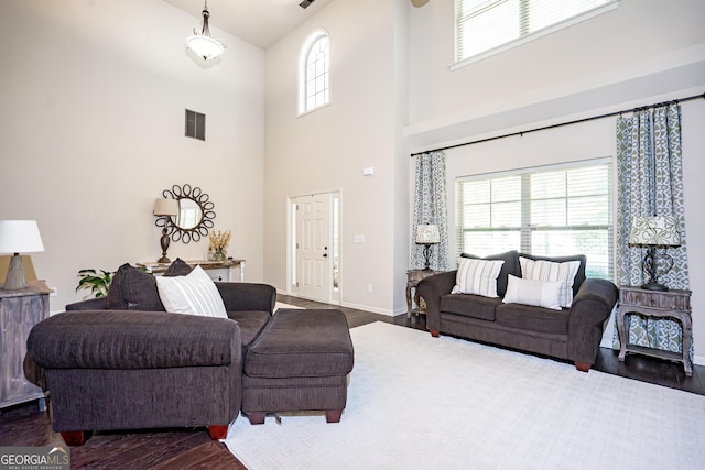 living room featuring dark hardwood / wood-style flooring and a towering ceiling