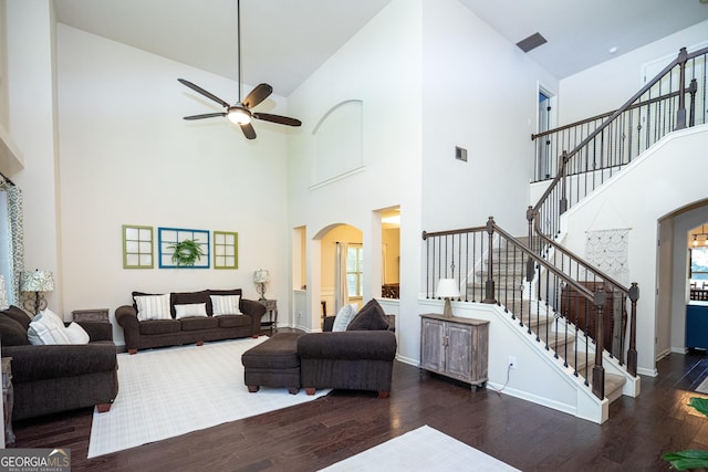 living room featuring dark hardwood / wood-style flooring, ceiling fan, and a high ceiling