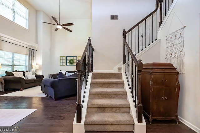 stairway with a high ceiling, hardwood / wood-style floors, and ceiling fan