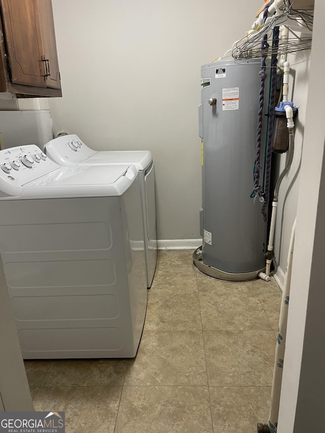 washroom featuring washing machine and dryer, electric water heater, light tile patterned floors, and cabinets