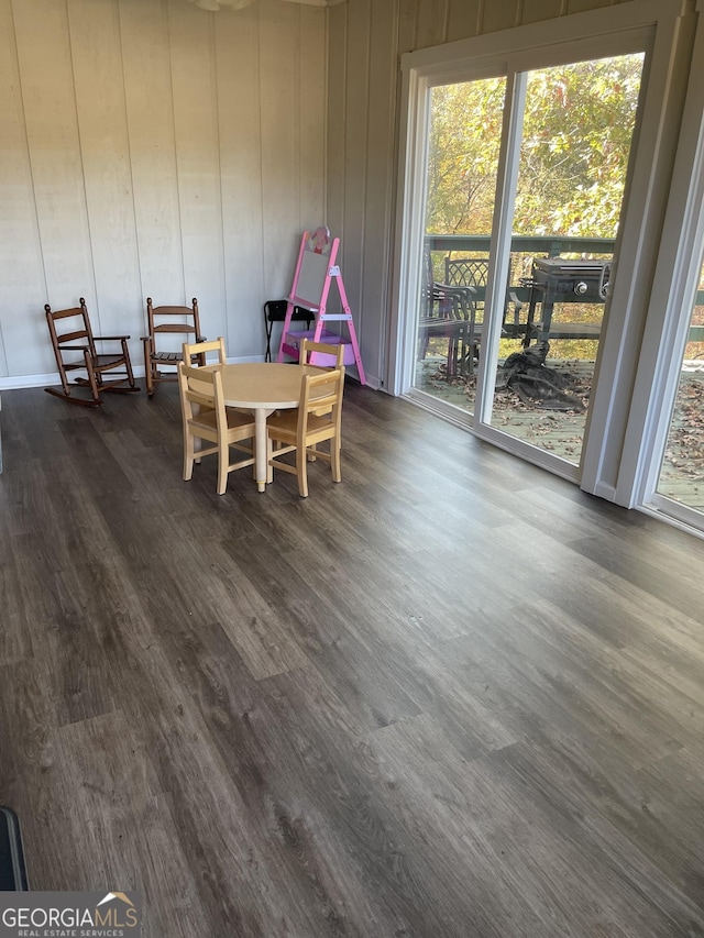 dining room with dark hardwood / wood-style flooring and wood walls