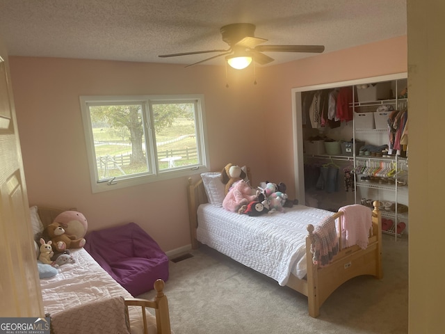 bedroom featuring ceiling fan, a closet, carpet, and a textured ceiling