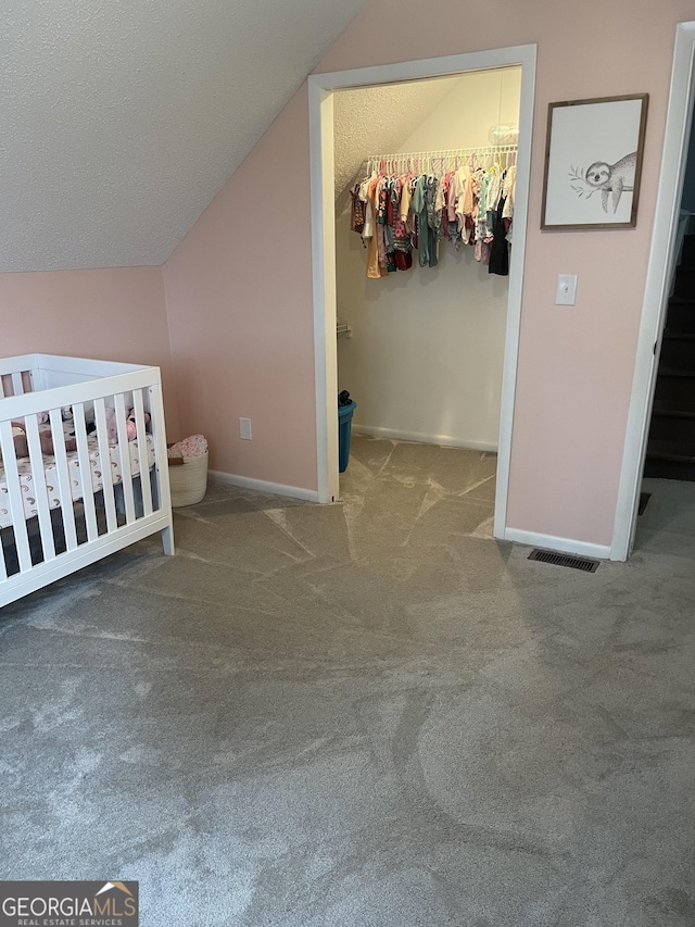 unfurnished bedroom featuring a textured ceiling, lofted ceiling, carpet floors, and a closet