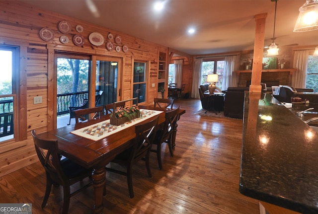 dining area featuring dark wood-type flooring, ceiling fan, decorative columns, and a wealth of natural light