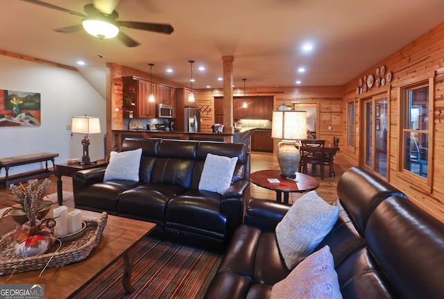 living room featuring wood-type flooring, ceiling fan, and wood walls