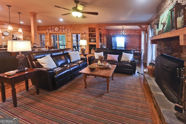 living room featuring a stone fireplace, ceiling fan, and wood walls