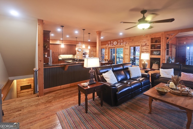 living room with ceiling fan, dark hardwood / wood-style flooring, sink, ornate columns, and wooden walls