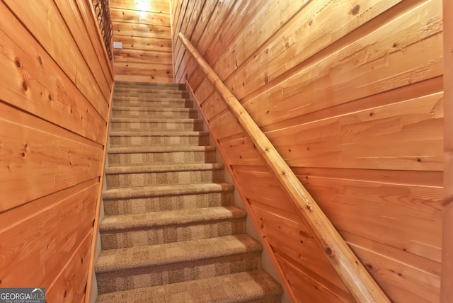 staircase featuring wood ceiling and wooden walls